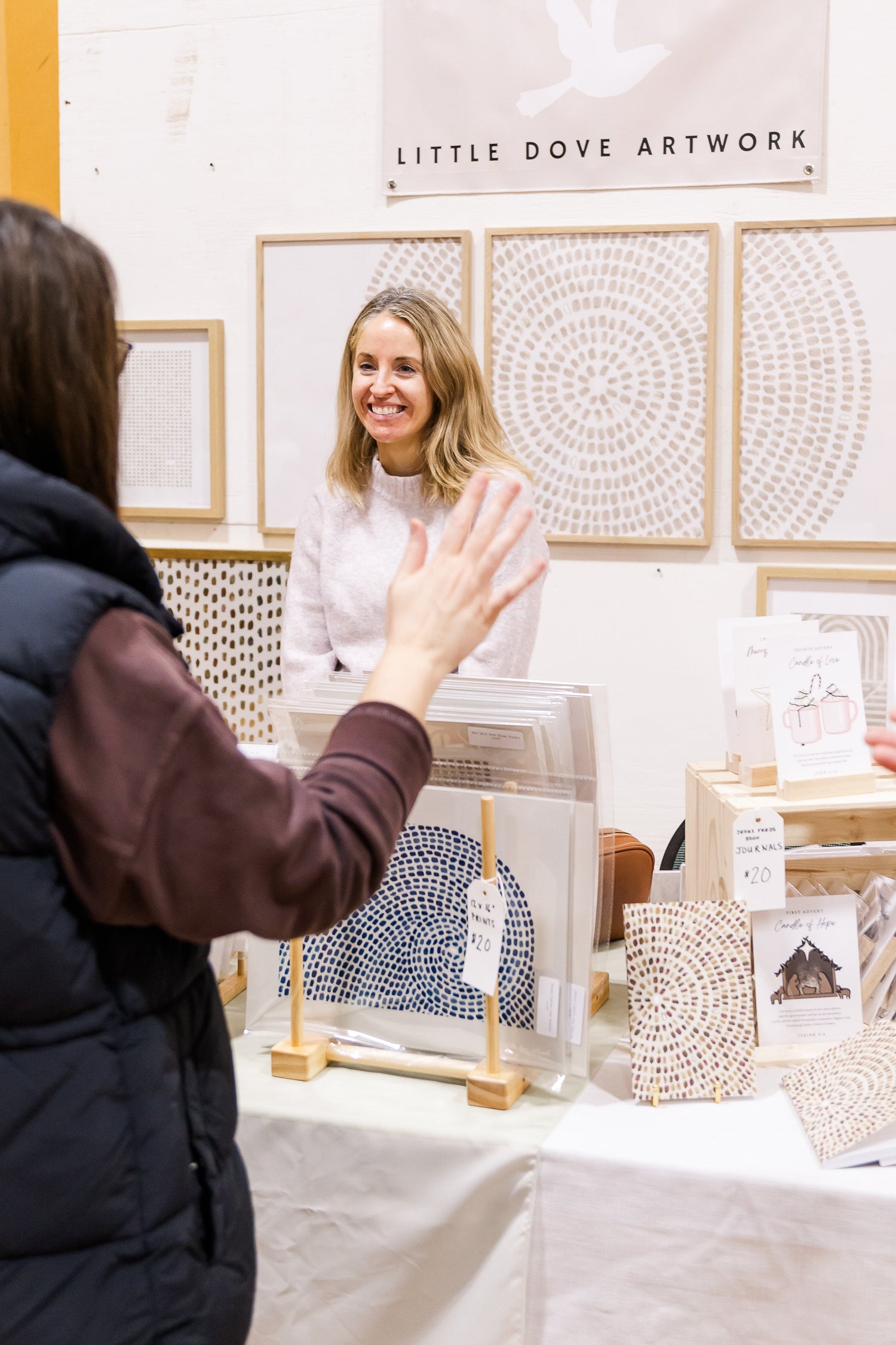 Woman interacting with art at a Little Dove Artwork booth.